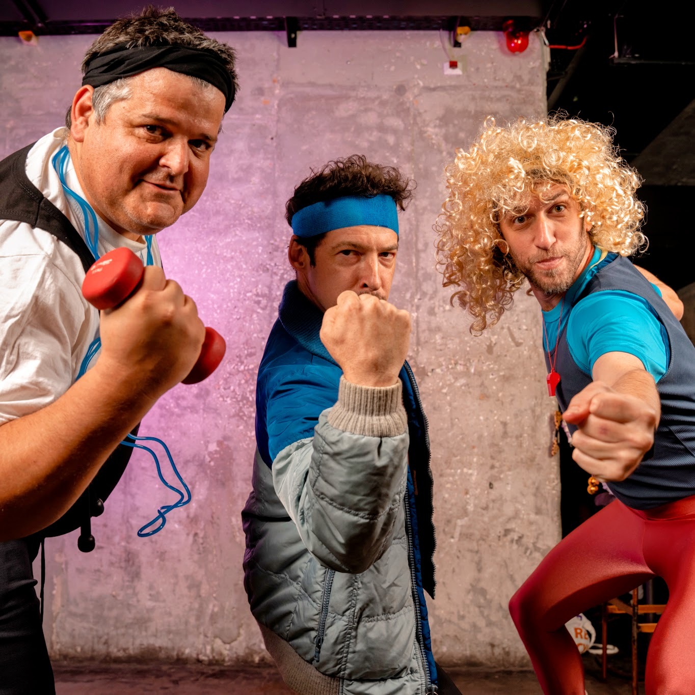 Three man dressed as 80s aerobic trainers at a party striking a pose as the camera